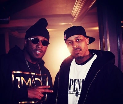 A picture of Yukmouth and Numskull in their black hoddie and black cap.